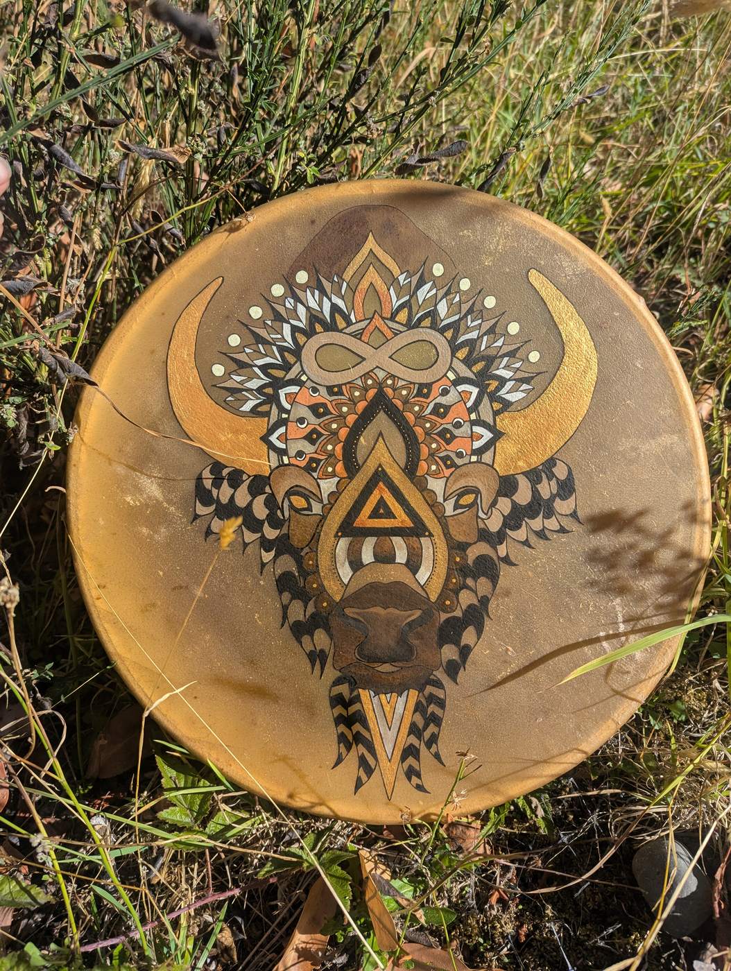 Hand drum painted with a gold and copper mandala bison